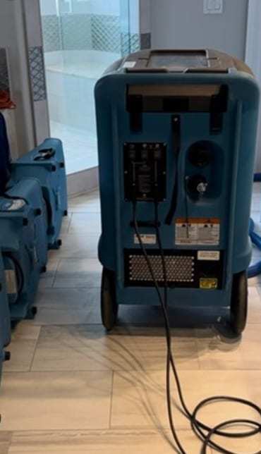 Dehumidifier and air movers drying a tiled bathroom